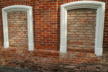 Aged brick wall with four arched bricked up windows with space for text.