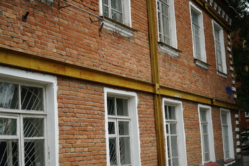 Fototapeta na wymiar Building with reinforced wall, strengthen old brick wall structure. Renovation and restavration of old facade