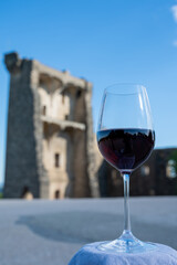 Glass of red dry wine and ruins of medieval castle of Châteauneuf-du-Pape ancient wine making village in France