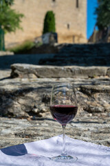 Glass of red dry wine and ruins of medieval castle of Châteauneuf-du-Pape ancient wine making village in France
