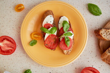 Caprese sandwich appetizer with fresh mozzarella, tomatoes, basil leaves. Italian mediterranean classic recipe close up. Top view food