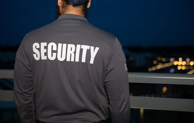 Obraz premium A rear view of a security guard walking through the street of the big city at night.