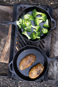 Outdoor camp cooking on cast iron pans with an open  wood burning flame