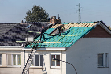 Ouvriers travaillant à l'isolation d'un toit - obrazy, fototapety, plakaty