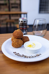 artistically presented croquettes on a plate with sauce in a pot