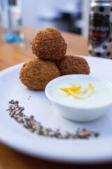 artistically presented croquettes on a plate with sauce in a pot