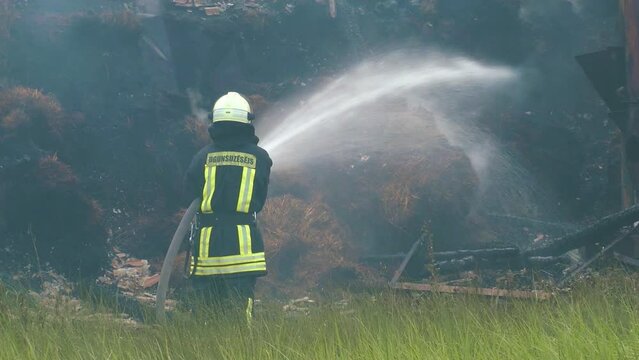 Fireman extinguish fire with the hose. Firefighters put out a burning grain forge.The grain dryer burned down. 