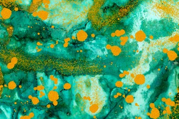 Gold dust and drops on green Alcohol ink fluid abstract texture fluid art with gold glitter and liquid.