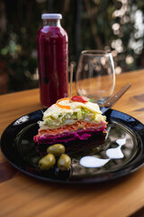plate with vegetable and olive lasagna, red fruit juice and glass on the table