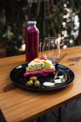 plate with vegetable and olive lasagna, red fruit juice and glass on the table
