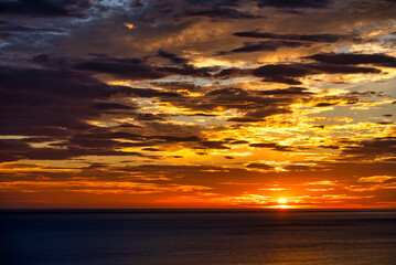 水平線に沈む夕日と夕焼けに照らされる雲