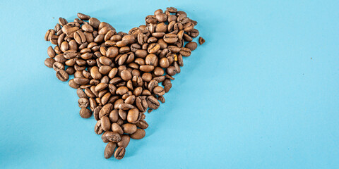 heart made with coffee beans over blue background with copy space or text area