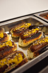 hot dogs with different sauces on a metal tray