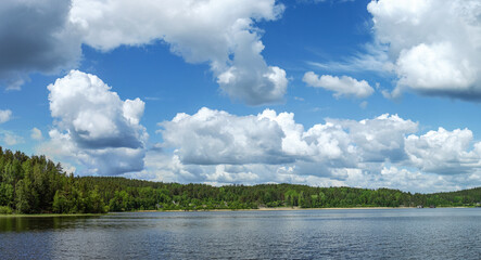 The landscape of a forest lake, the sky in the clouds is reflected in the water
