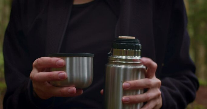 Woman Rests Alone In Pine Forest And Drinking Hot Tea From Steel Thermos Cup, Natural Moments And Solo Activity In Nature