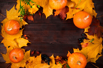 Autumn background. Frame from ripe pumpkins and fallen leaves on wooden boards. Harvest and...