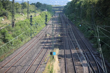 Railroad tracks perspective, four railway lines powered by electricity with bridge on the background