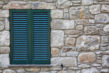 Fototapeta na wymiar Old green shutter on a stone building