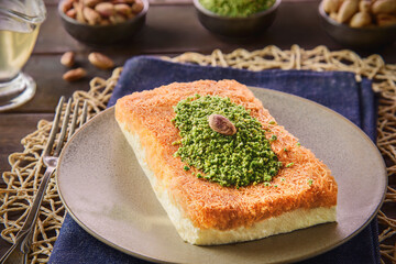 Arabic Cuisine; Traditional Middle Eastern Cheese Kunafa Dessert. A delicious pastry consisting of soft melty cheese and shredded phyllo dough. Served with sugar syrup and crushed pistachio.