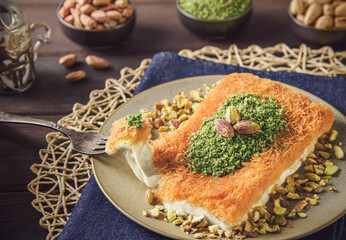 Arabic Cuisine; Traditional Middle Eastern Cheese Kunafa Dessert. A delicious pastry consisting of soft melty cheese and shredded phyllo dough. Served with sugar syrup and crushed pistachio.