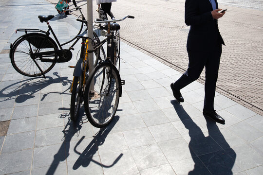 businessman walking on a sidewalk with parking bicycles