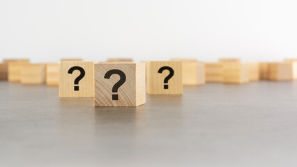 cube with question mark on wooden background. space for text