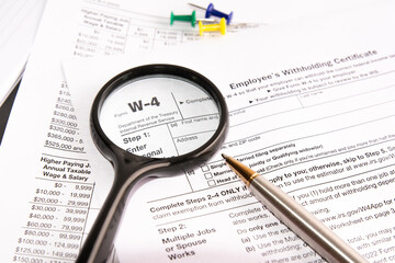 blank form W-4, magnifier and a pen on table. tax season