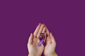 World Alzheimer's day. September 21. International Epilepsy Day. Adult hands holding purple ribbon on purple background. World Lupus Day and world cancer