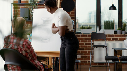 Art teacher training senior woman to draw artwork in art class program, using creativity and artistic instruments. Drawing lesson practice on canvas to learn new skills for development.