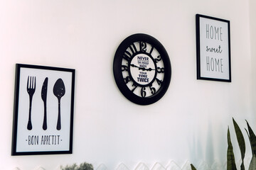 Two posters with inscriptions Bon Appetit and Home Sweet Home with clock hangung on the white modern kitchen wall. Decoration concept
