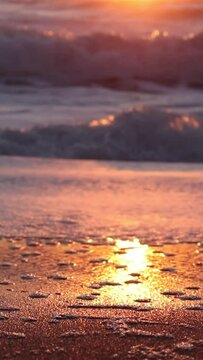 Vertical shot of sunset with sea waves and bubbly sand