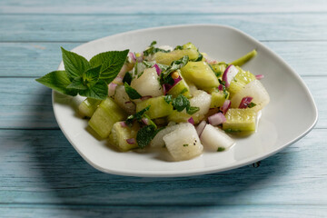 Honeydew melon salad with cucumber and mint, served on a plate.
