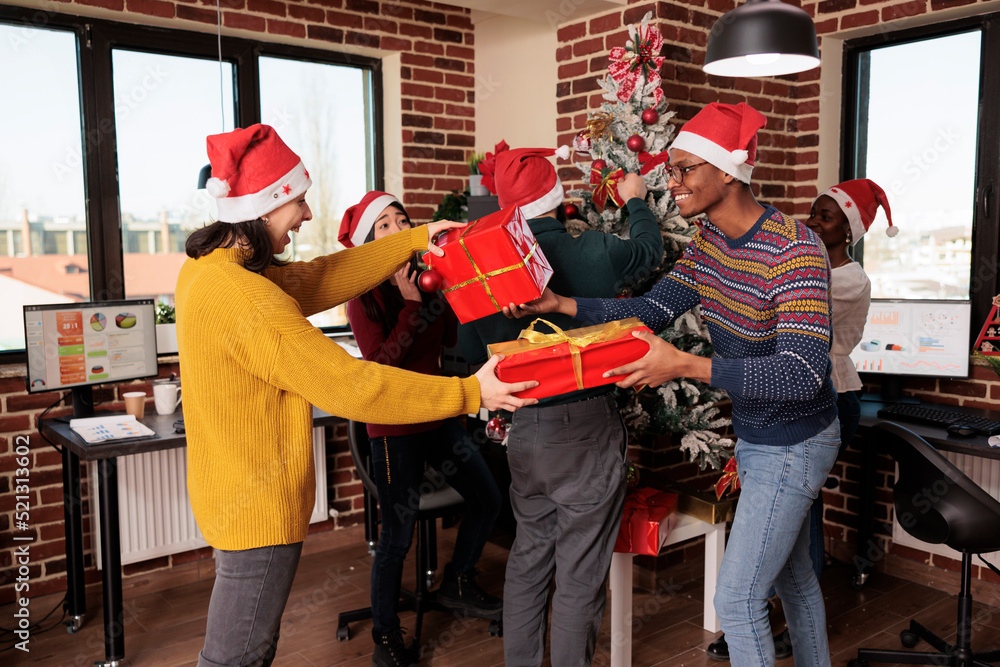 Wall mural diverse group of coworkers exchanging holiday gifts at christmas celebration in business office. col