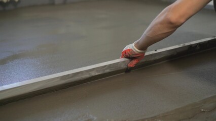 Production of cement floor. Floor screed in the apartment. Leveling the floor screed with metal...