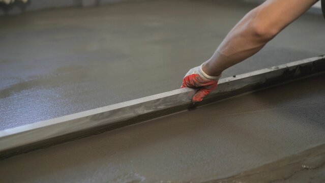 Production of cement floor. Floor screed in the apartment. Leveling the floor screed with metal wire.