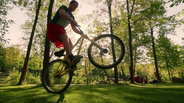 Cyclist slow jumps on the rear wheel against the background of the sun.