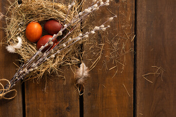 Painted Easter chicken eggs in a nest and willow branches. Holiday Easter concept background. High quality photo