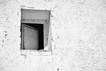 Ventana entreabierta de madera en la fachada de una vieja casa