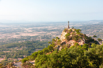 cross on the mountain with reflections of the sun illuminating with green and blue sky