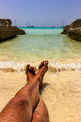 feet on a turquoise paradise beach and stone pool