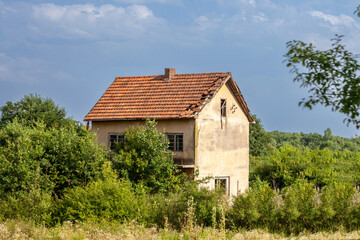 Fototapeta na wymiar Old Residential house building from an abandoned farm in Serbia, in the middle of a rural countryside. The region of Balkans is hit by a severe rural exodus and emigration deserting the area....