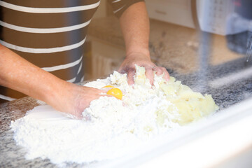 Obraz na płótnie Canvas Hands Kneading Raw Dough, Flower, and Eggs on the Table. Homemade Culinary Prep.