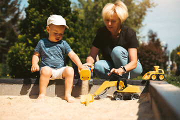 Grandmother and child having fun together, playing in sandbox. Generation and childhood concept. Happy family symbol