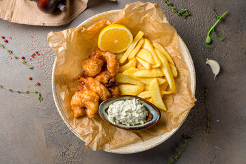 fish and chips with french fries and tartar sauce on brown table top view