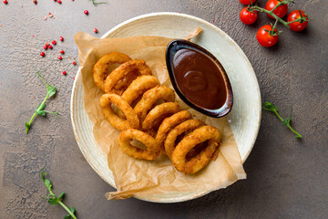 Onion rings in batter with bbq sauce on plate top view
