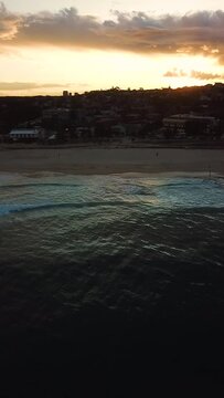 Golden sunset reflected on surface of undulating ocean on summer evening in Maroubra beach Sydney