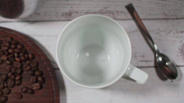 Pouring hot coffee in a white cup of coffee beans