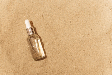 Cosmetic bottle with a pipette on the sand. against the background of sand.