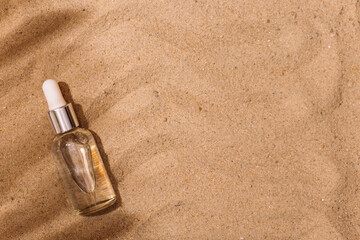 Fototapeta na wymiar Cosmetic bottle with a pipette on the sand. against the background of sand.