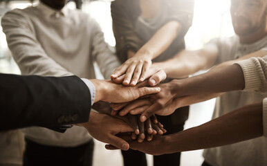Businesspeople with their hands together in a huddle pile showing support, teamwork and close...